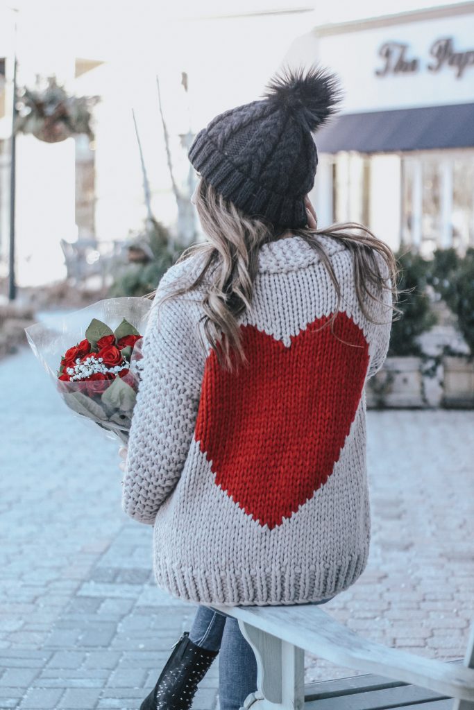 Cute Valentine's Day Sweaters featured by top US fashion blog House of Leo Blog; Image of a woman wearing Chicwish sweater, Red Dress Boutique jeans and Amazon boots.
